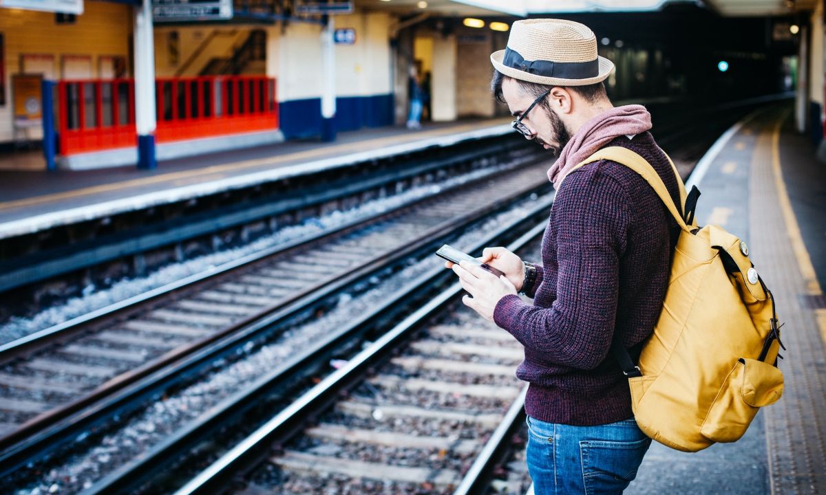 Millennial esperando el tren para viajar con mochila