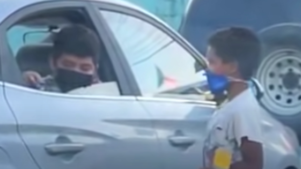 Niño juega con otro que limpia parabrisas